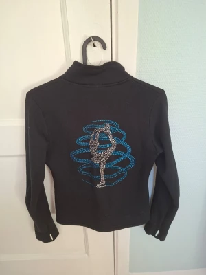 Konståknings fleece med biellman tryck - Jättefin fleece för konståkning från Ny2 sportswear. Strl CL vilket motsvarar ungefär 150 cm eller 10-12år. Mycket nopprig på insidan som inte synns vid användning, och lite nopprig på utsidan som bara synns om man tittar nogrannt på nära håll.