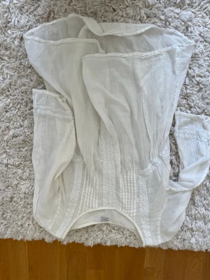 Vit blus med spetsdetaljer Kappahl - Säljer en vit blus från Kappahl i storlek S, med fina spetsdetaljer och veck framtill. Blusen har lång ärm och är gjord i ett tunt, luftigt material som känns skönt mot huden. Perfekt för dig som gillar romantisk och bohemisk stil. Bilden är upp och ner…men tröjan är i bra skick!