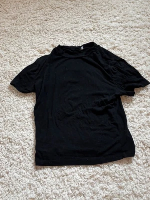 Svart basic t-shirt i bomull - En enkel svart t-shirt med korta ärmar och rund hals. Tillverkad i mjuk bomull och har en klassisk passform som funkar till det mesta. Perfekt att styla med jeans eller under en skjorta.