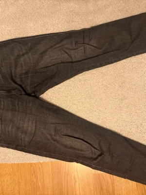 Mörkgrå jeans från Replay - Säljer ett par mörkgrå jeans från Replay med klassisk femficksmodell och raka ben. Jeansen har snygga kontrastsömmar och är tillverkade i mjuk denim som sitter skönt. Perfekta för dig som gillar stilrena och tidlösa jeans. I storlek 32/32 använda fåtal gånger 
