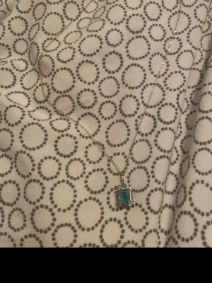 Silverhalsband med turkos sten - Snyggt halsband i silverfärg med en rektangulär turkos sten som hänge. fick den som present så vet ej vart den är köpt