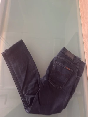 Svarta Grim Tim Nudie Jeans - Säljer ett par svarta jeans från Nudie Jeans med klassisk femficksmodell. Mycket bra skick och snygg tvätt, för små för mig. W30 