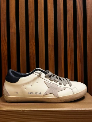 Golden Goose Superstar sneakers beige - Stilrena Golden Goose Superstar sneakers i beige läder med grå mockadetaljer och stjärna på sidan. Skon har grå snören, svart hälparti och en vintage-inspirerad sula. Perfekt för dig som gillar en avslappnad men trendig look.