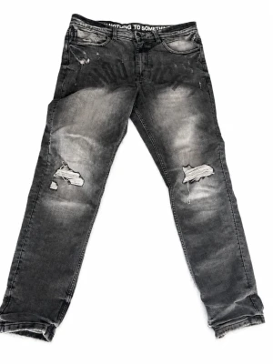 Grå slitna slim fit jeans - Säljer ett par grå slim fit jeans med slitningar och hål på båda benen äkta från hoodrich köpt på JD. Säljer eftersom jag växt ut. W 32 Length 32