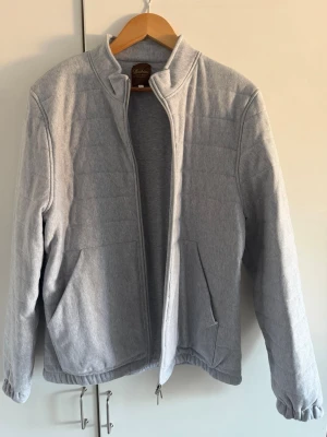 HELT NY jacka från Stenströms - Snygg ljusgrå jacka från Stenströms med dragkedja framtill och två fickor. Jackan har en enkel, stilren design och är tillverkad i mjuk bomull. Använd 2 gånger men säljs för den är för liten, nypris ligger på 3499 SEK 