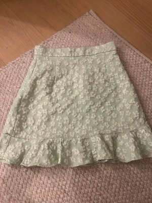 Ljusgrön blommig kjol med volang - Supersöt ljusgrön kjol med vita blommor i broderat tyg och volang längst ner.💚💚💚