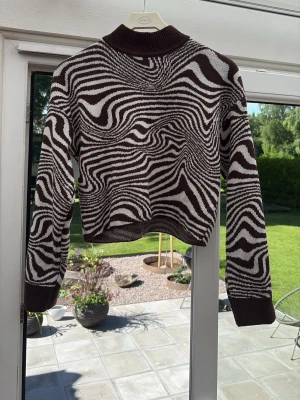 Zebramönstrad stickad tröja - Säljer en stickad tröja med zebramönster i mörk brun och vitt. Tröjan har bruna ribbade muddar vid ärmslut, nederkant och hals. Något kort i midjan, men lite längre i ärmen. Inte alls stickig, och perfekt till hösten🌼