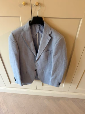 Flannel Bay Napoli Kavaj – Vitale Barberis Canonico Super 120’s - Snygg ljusblå kavaj i ull från Vitale Barberis Canonico, tillverkad i Italien. Klassisk modell med två knappar, fickor fram och slimmad passform. Perfekt för en stilren och modern look. Nypris 7.000kr
