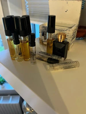 Parfymprover och miniflaska Valentino - Flera parfymprover i små glasflaskor med svart lock samt en miniflaska från Valentino med svart och guld design. Perfekt för att testa olika dofter eller ha med sig i väskan. Innehållet varierar i färg från ljusgul till bärnstensfärgad.