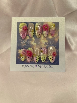Hana (M);Medium Almond - Snygga handgjorda press-on naglar i en medium lång mandelform med pastellfärger som rosa, gul och nude. Dekorerade med 3D-blommor, gulddetaljer och svarta prickar för en unik look. Perfekt för dig som vill ha något extra till naglarna!M: 16 mm, 12 mm, 12,5 mm, 11,5 mm, 10 mm