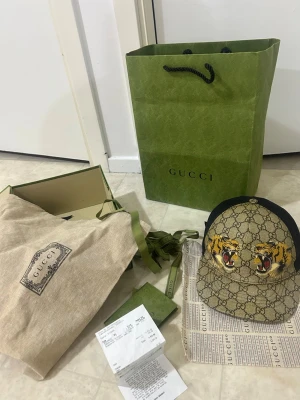 Gucci keps med tigertryck - Gucci tigerkeps gammal modell och självklart äkta allt tillbehör medföljer också. Hör av er vid funderingar och priser kan diskuteras 