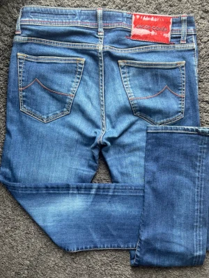 Jacob Cohën Nick - Jacob Cohën Nick i en fantastisk tvätt! Perfekta till sommaren till en kavaj. Handgjorda i Italien. 🧵 Märke: Jacob Cohën - Nick 📏 Storlek: 33. Slim fit. 🧩 Material: 92% bomull 8% Elastan.  📐 Mått: Midja 40cm, Längd 100cm, Benslut 16,5cm, Lår 25cm. ✅ Skick: 9/10 - Denim och allt i toppskick. Lite hår har fallit bort från patchen vilket är det som inte dessa en 10/10 i skick.  💰 Nypris: Ca 5000 kr. ‼️Skickas snabbt‼️ Dessa jeans är ett riktigt kap för den som verkligen vet vad riktig kvalitet är. 