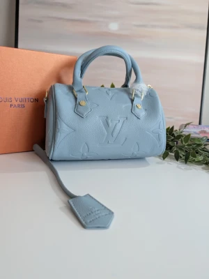 Iouis Vuitton Speedy Bandoulière Monogram 🩵 - ✨ Ljusblå miniväska i präglat läder! ✨ Säljer en helt ny och oanvänd handväska i en magisk ljusblå färg. Den är gjord i mjukt kvalitetsläder med vackert präglat mönster och fina gulddetaljer. Plastskyddet sitter kvar på handtaget. Originalbox medföljer. ⚠️ OBS: Hänglås och nyckel saknas tyvärr. Därför säljer jag den betydligt billigare än normalt. Ett perfekt tillfälle att göra ett riktigt fynd!