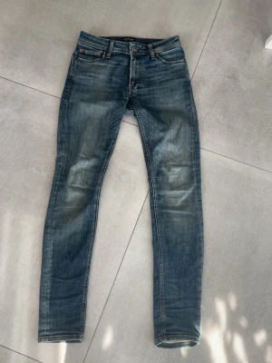 Jack and Jones jeans  - Halloj! Säljer ett par blå slim fit jeans från Jack and Jones  med klassisk femficksmodell och snygg slitning/tvätt på låren. Jeansen har normal midja, smala ben och är gjorda i mjuk denim med lite stretch för extra skönhet. Perfekta till en clean och laidback outfit. Skicket är 10/10 och storleken är 30/32!! Otroligt snygga jeans! Hör av dig vid mer frågor eller funderingar🤩mvh Ga