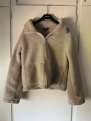 Teddyjacka - Mysig ljusbeige teddyjacka från 157 med dragkedja framtill och hög krage som man även kan vika ner. Jackan har två stora fickor framtill. Är i storlek S men skulle säga att den passar xs också. Nästan oanvänd!Väldigt skön och snygg!! Pris kan diskuteras vid snabbt köp🩷