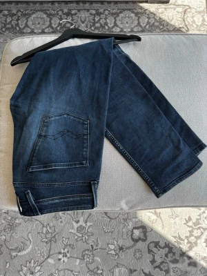 Mörkblå jeans från Replay - Snygga mörkblå jeans från Replay med raka ben och klassisk femficksmodell. Jeansen har diskreta slitningar och kontrastsömmar samt en unik bakficka med vågig söm. Perfekta till en avslappnad stil och tillverkade i mjuk denim.