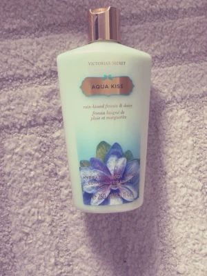 Victoria's Secret Aqua Kiss lotion - Aqua Kiss body lotion från Victoria's Secret med doft av regnvåt fresia och prästkrage. Flaskan är ljusblå med blommotiv och har ett guldfärgat lock. Innehåller 250 ml återfuktande lotion som ger huden en fräsch och blommig känsla. Ej använt bara provad!🩷