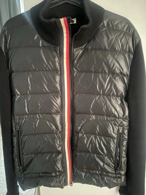 Svart pufferjacka från Moncler - Moncler cardigan i storlek M. Perfekt inför sommaren! Jackan är i väldigt bra använt skick, lättare tecken på användning finns (se bilder). Hör av er vid intresse eller önskan om fler bilder!