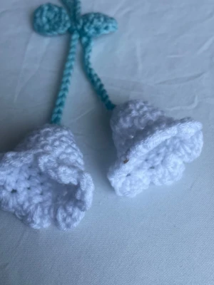 Virkad håraccesoar/ bag charm blomma - Supersöt handvirkad hårsnodd/ bag charm med två vita blommor och gröna blad. Blommorna är formade som klockor och sitter fast i gröna virkade snören. Perfekt för att piffa upp frisyren eller handväskan/ hörlurarna med en unik accessoar i bomullsgarn.