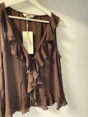 topp från Only  - Brun topp/blus från Only, prislappen är kvar, den har inte kommit till användning. Orginalpris är 350kr