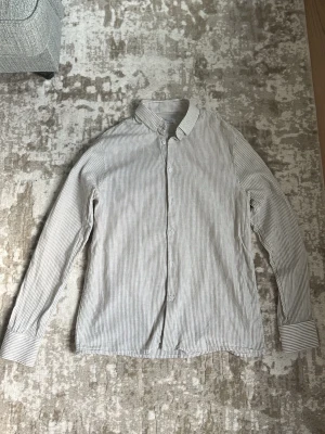 Randig linneskjorta beige/vit  - Linneskjorta från Approach med tunna beige ränder. Passform slimfit. Perfekt för en clean och stilren look.