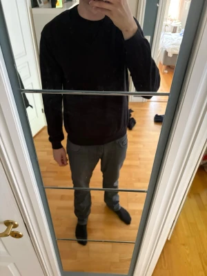 Svart V-ringad tröja från Gant - Klassisk svart V-ringad tröja från Riley. Tröjan har långa ärmar, ribbade muddar och en diskret logga på bröstet. Perfekt att bära över en skjorta eller t-shirt för en clean och stilren look. Hör av dig vid funderingar 