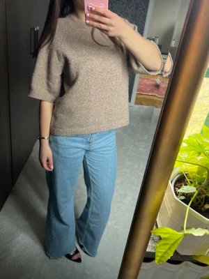 Beige stickad tröja med halvlånga ärmar - Mysig beige stickad tröja med halvlånga ärmar och avslappnad passform. Lite nopprig men går enkelt att ta bort
