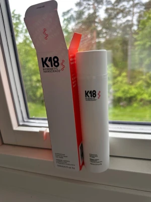 K18 Biomimetic Hairscience hårprodukt - K18 Biomimetic Hairscience hårprodukt i en vit cylinderformad plastflaska med svart och röd text. Flaskan rymmer 150 ml och kommer i originalförpackning. Perfekt för dig som vill vårda och stärka håret med avancerad hårteknologi.