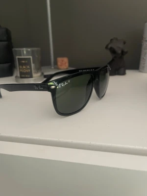 Svarta Ray-Ban solglasögon Boyfriend - Snygga svarta Ray-Ban solglasögon i klassisk Wayfarer-modell med gröntonade polariserade glas. Bågarna är i plast och har Ray-Ban-logga på sidan och linsen. 