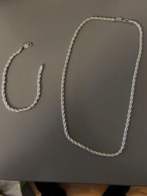 Silverfärgat tvinnat halsband - Säljer ett stilrent halsband i silverfärg med tvinnad kedja. Halsbandet har en klassisk karbinhake och en elegant, enkel design som passar till många olika stilar. Materialet ser ut att vara metall med en blank finish.