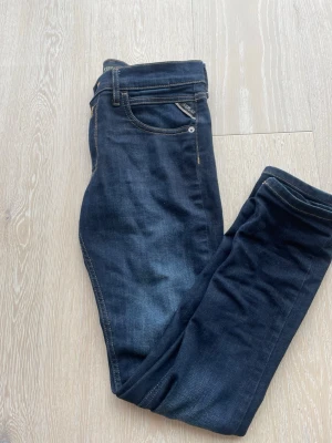 Mörkblå jeans från Replay - Snygga mörkblå jeans från Replay med klassisk femficksmodell och kontrastsömmar. Jeansen har en smal passform och är tillverkade i ett mjukt denimtyg som ger en bekväm känsla. Perfekta för dig som gillar stilrena och tidlösa jeans.