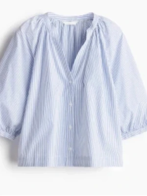 Trendig blårandig blus - Luftig blus med tunna blå och vita ränder, knappar framtill och voluminösa trekvartsärmar. Avslappnad passform och rundad halsringning med lätt rynk. Perfekt för en fräsch och stilren look.