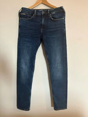 Mörkblå slim fit jeans från Jack & Jones - Snygga mörkblå slim fit jeans från Jack & Jones. Jeansen har normal midja, smala ben och är tillverkade i stretchigt denim för extra komfort. Perfekta till en avslappnad och trendig look. Byxorna är ALDRIG andvända