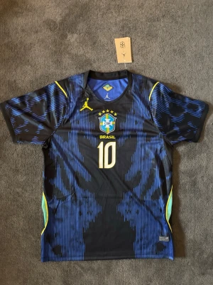 Brasilien VM 26/27 borta Neymar Jr  - Fotbollströja med Neymar JR på ryggen. Tröjan är helt ny med tagg kvar och i perfekt skick. Storlek M. Perfekt för dig som är supporter, samlar på fotbollströjor eller vill ha en snygg tröja till träning och vardag.                                                   🔹 Storlek M.                                                                   🔹 Helt ny med tagg.                                                     🔹 Skickas inom 24 timmar         Vid intresse eller frågor är det bara att skicka 👍