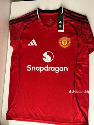 Manchester United matchtröja Adidas - Stilren och högkvalitativ fotbollströja inspirerad av Manchester Uniteds klassiska design. Tröjan är tillverkad i ett bekvämt och ventilerande material som passar både för träning och vardagsbruk. Storlekar: S, M, L Skick: Ny