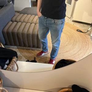 Ljusblå raka jeans tiger of sweden - Säljer ett par ljusblå jeans med rak passform och klassisk femficksdesign. Jeansen har normal midja och är tillverkade i denim med en lätt tvättad look. Perfekta för en avslappnad stil och passar till det mesta i garderoben.