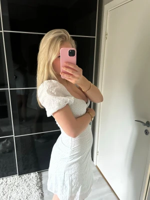 Vit kortklänning med puffärm - Söt vit kortklänning med små blommiga detaljer och puffiga armar. Perfekt till skolavslutningen 💕🌸