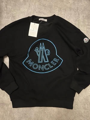 Svart sweatshirt från Moncler med blått tryck - Svart tröja från Moncler. Storlek S. Vide eventuella frågor, skriv! Pris kan diskuteras vid snabb affär!