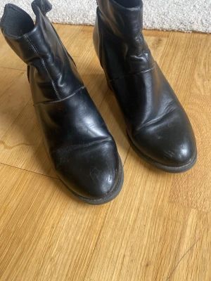 Svarta boots  - Snygga svarta boots med rund tå och diskret söm över foten. Klassisk modell med något högre skaft och dragkedja på insidan. 