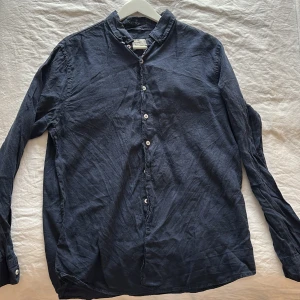 Mörkblå linneskjorta från Dressmann - Snygg mörkblå skjorta från Dressmann i premium linne. Skjortan har klassisk krage, knappar framtill och långa ärmar. Perfekt för dig som gillar en avslappnad men stilren look.