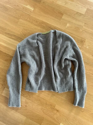 Grå/brun stickad kofta - Mysig grå/brun kofta i ribbstickat material med öppen front och långa ärmar. 