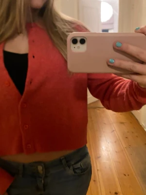 Koralröd cropped kofta  - Säljer en korallröd cropped kofta från primark .Koftan har rund halsringning, långa ärmar och knappar framtill. Tillverkad i mjuk och skön ullblandning, perfekt för lager på lager och en trendig look. Den är liten i storleken så passar till med xs eller s i vanliga fall.