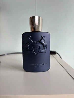 Parfums de Marly Layton EdP 125ml - Exklusiv parfym från Parfums de Marly, Layton Eau de Parfum. Flaskan är matt mörkblå med silverfärgat lock och har två upphöjda hästar på framsidan samt texten '1743'. Doften är elegant och lyxig, perfekt för dig som gillar unika parfymer.