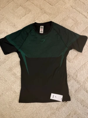 Gymshark Onyx V5 Tröja – Mörkgrön och svart - Gymshark Onyx V5 Tröja – Mörkgrön 👕 Storlek: M 💚 Färg: Mörkgrön ✨ Skick: Nyskick – endast testad 🧵 Modell: Onyx V5