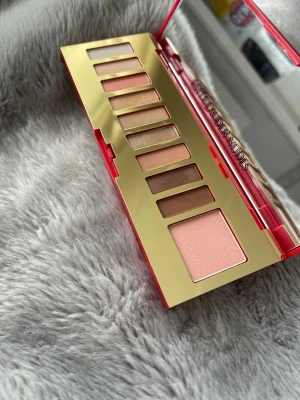 Estée Lauder ögonskuggspalett nude - Ögonskuggspalett från Estée Lauder med åtta nyanser i nude, rosa och bruna toner. Paletten har ett elegant rött fodral med gulddetaljer och stor spegel. Perfekt för att skapa naturliga och mjuka ögonlooks.