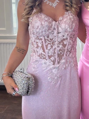 Jättefin balklänning!! - Säljer nu min jättefina balklänning med spetsdetaljer! Rosa/lila med glitter! Klänningen är insydd för bättre passform☺️ Den är även uppsydd fram nertill vid fötterna och med ett längre släp. Skulle säga att den passar för 160-170 cm långa! Insidan på släpet har blivit lite smutsigt men absolut inget som syns. Nypris är ca 1500 + 1000 för att få den insydd. 