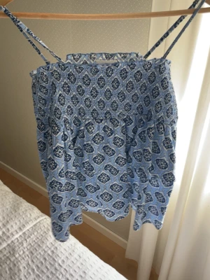 Blå mönstrad linnetopp Gina Tricot - Söt blå linnetopp från Gina Tricot med smala axelband och ett detaljerat mönster i vitt och mörkblått. Den sitter som en S🥰