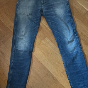 Replay anbbas slitningar - Snygga blå slim fit jeans med slitningar och tvättade detaljer på både fram- och baksida. Klassisk femficksmodell med normal midja och dragkedjegylf. Perfekta för en avslappnad och trendig look.
