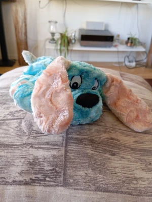 Blå och rosa mjukishund - Söt mjukishund i plysch med blå kropp och stora, fluffiga rosa öron. Hunden har broderade ögon och svart nos. Perfekt som gosedjur eller dekoration i rummet. Mjuk och gosig att krama.