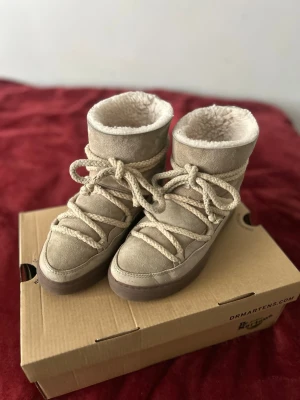 Beige fårskinnskängor från Inuikii  - Säljer ett par beige kängor från Iniukii med mjukt fårskinnsfoder och grova snören. Yttermaterialet är mocka och sulan är i gummi, och ull. Perfekta för kalla dagar och ger en riktigt cozy vibe. Klassisk hög modell med rund tå och robust känsla.🩷🩷